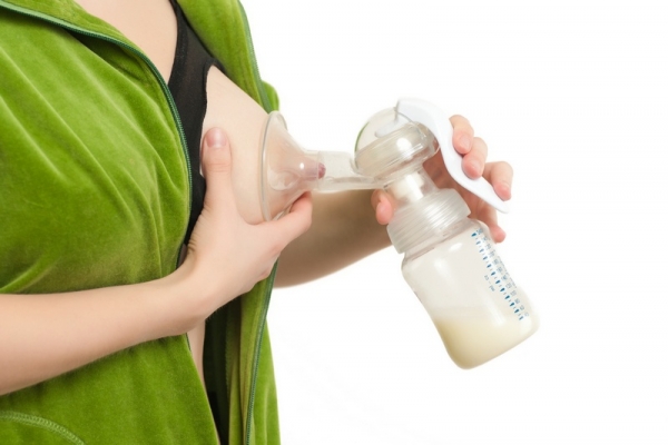 young woman pump out milk from full breast to bottle