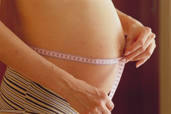 Беременная измеряет объем живота  - фото
