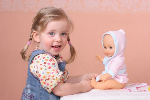 Девочка играет с куклой - фото