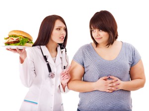 Женщина с гамбургером возле доктора (фото: Fotolia)