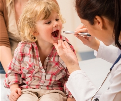 Доктор осматривает горлышко ребенка - фото