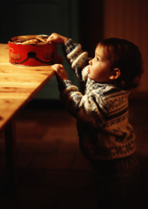 Малыш тянется к печенью на столе - фото