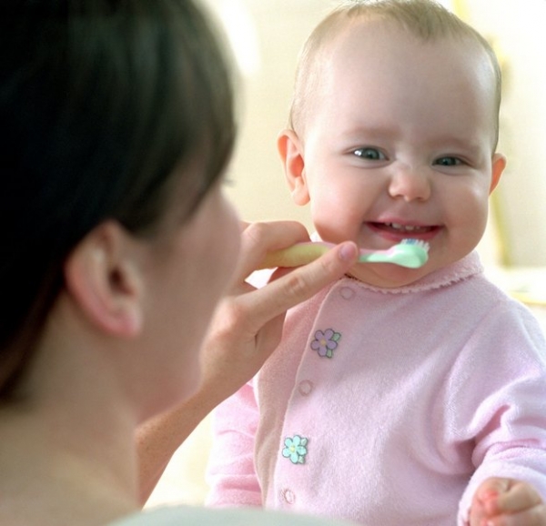 Мама чистит зубы младенцу - фото