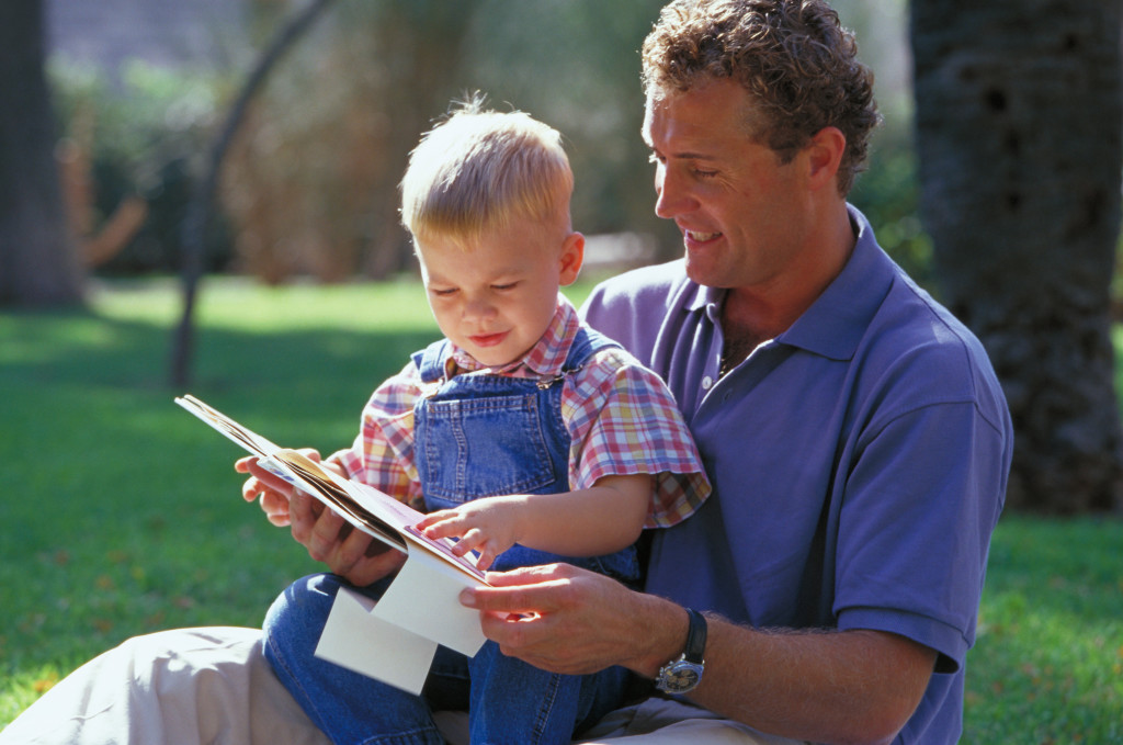 Папа с маленьким сыном читают книгу - фото
