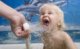 Малыша поливают прохладной водой из душа