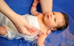 Ребенка купают в синей ванночке