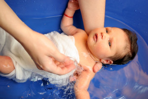 Ребенка купают в синей ванночке