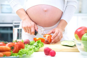 Беременная женщина нарезает овощи