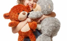Маленькая девочка держит в руках мягкие игрушки - медвежат. фото