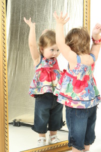 Маленькая девочка смотрится в зеркало - фото