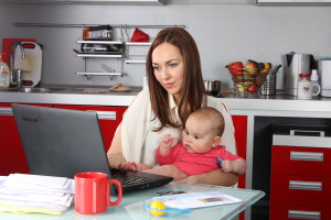 Мама с маленьким ребенком на руках у компьютера - фото