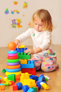 Маленькая девочка строет башню из конструктора - фото
