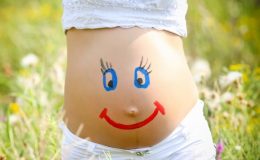 Живот беременной женщины с нарисованными маркеров глазками и ртом - фото