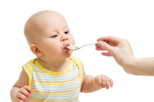 Ребенка кормят кашей из ложечки - фото