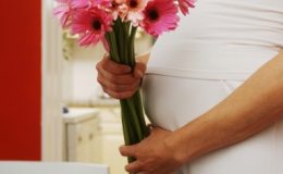 Букет цветов на фоне живота беременной - фото