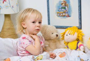 Маленькая девочка сидит в кровати с больным горлом - фото