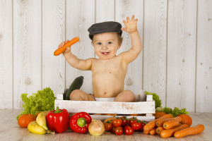 Маленький ребенок сидит в ящике с овощами - фото