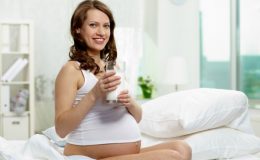 Беременная женщина держит в руках стакан кефира