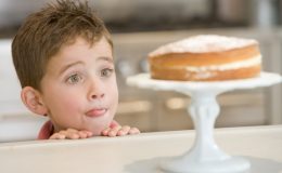 Мальчик с восторгом смотрит на торт на столе