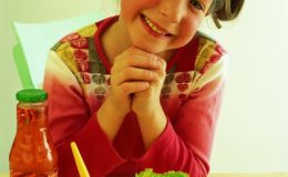 Девочка перед обеденным столом, на столе салат из овощей - фото