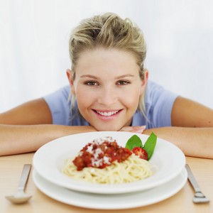 Женщина сидит за столом с тарелкой спагетти - фото