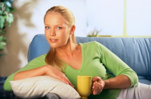 Молодая женщина сидит на диване и держит в руках чашку - фото