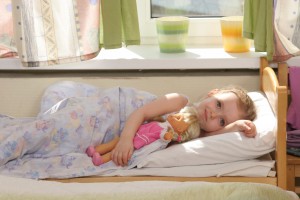 Девочка засыпает с куклой в кровати - фото
