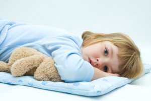 Маленькая девочка лежит в постели - фото