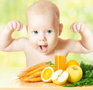 Маленький ребенок за столом с овощами, фруктами и соком - фото