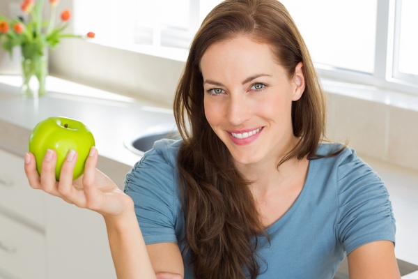 Женщина держит яблоко в руке - фото