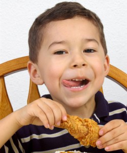 Мальчик ест курицу - фото