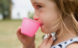 Девочка пьет с чашки - фото