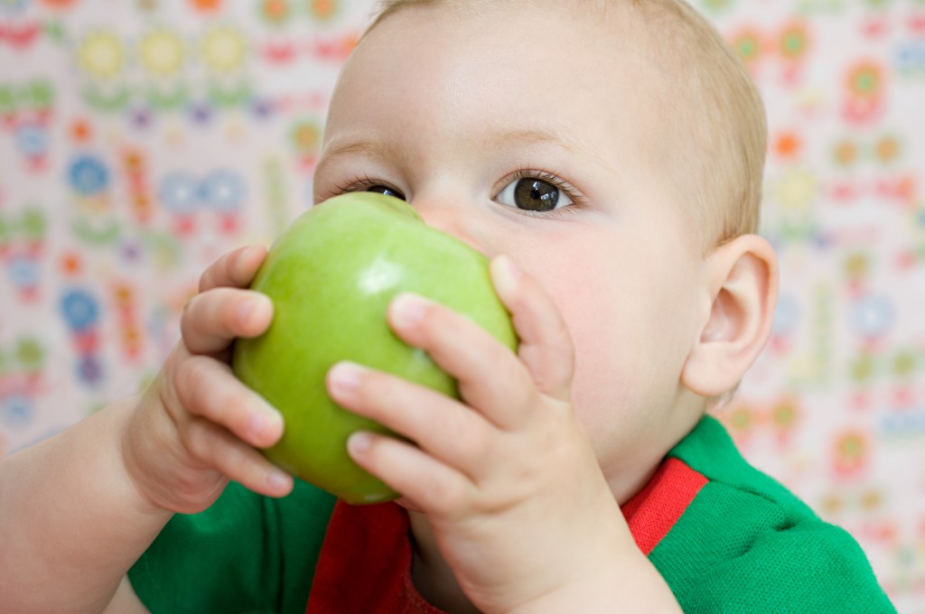 Ребенок кусает яблоко - фото