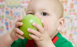 Ребенок кусает яблоко - фото
