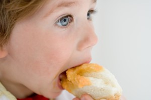 Мальчик ест булочку - фото