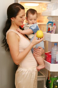 Мама держит на руках маленького мальчика и показывает ему яблоко - фото