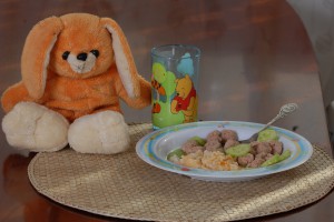 Еда на тарелочке для ребенка и мягкая игрушка рядом с тарелкой - фото