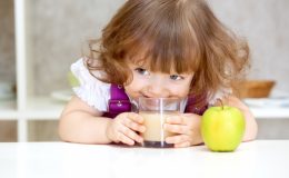 Маленькая девочка пьет яблочный сок - фото