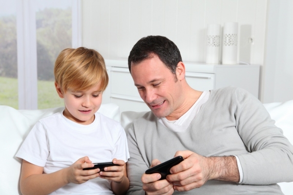 Отец с сыном играют на планшете - фото