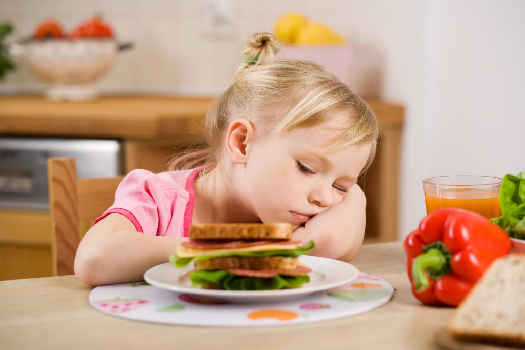 Девочка возле тарелки с едой - фото