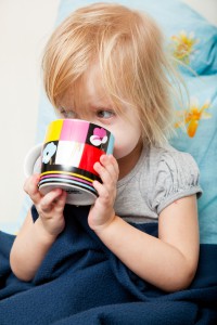 Маленькая девочка пьет из чашки 