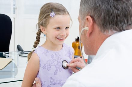 Лікар прослуховує маленьку дівчинку - фото