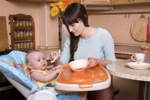 Мама кормит пюре маленького ребенка - фото