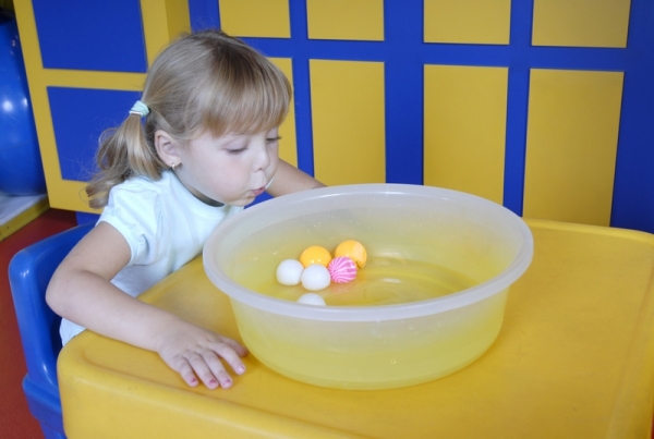 Девочка играет с шариками в воде - фото