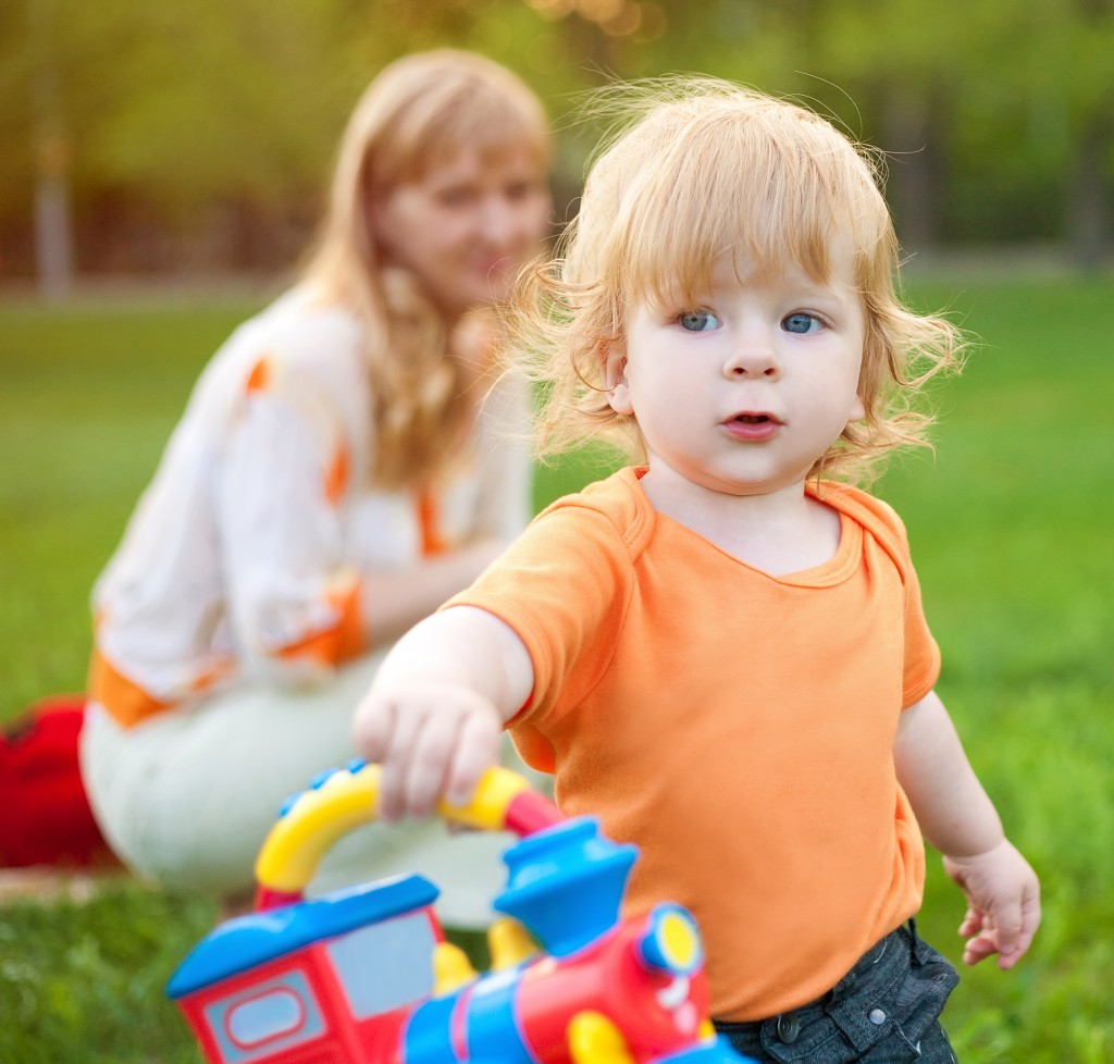 Маленький ребенок на прогулке с игрушкой в руках - фото