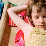 Девочка на пляже лежит с закрытыми глазами - фото
