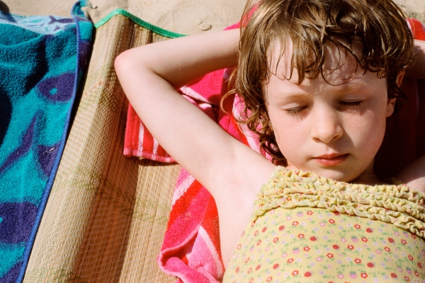 Девочка на пляже лежит с закрытыми глазами - фото