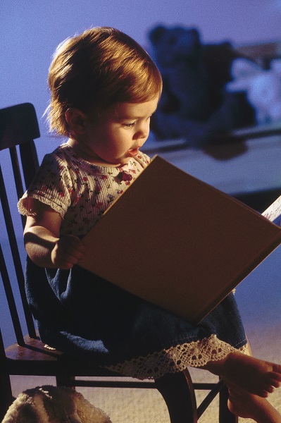 Маленькая девочка читает книгу - фото