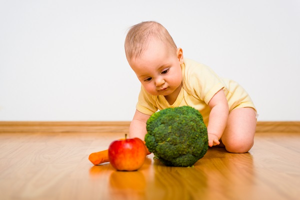 Маленький ребенок играет с овощами - фото