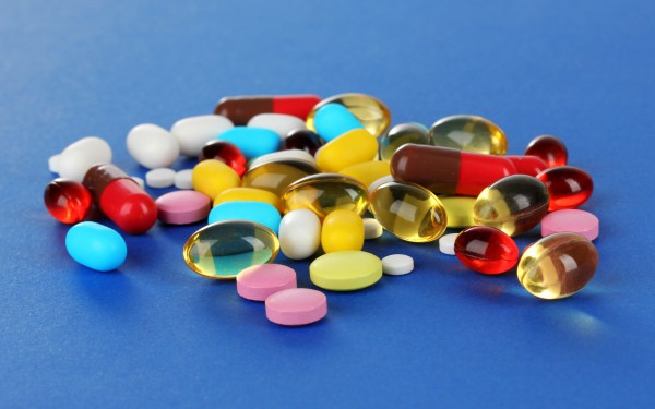 Разноцветные таблетки на синем фоне - фото
